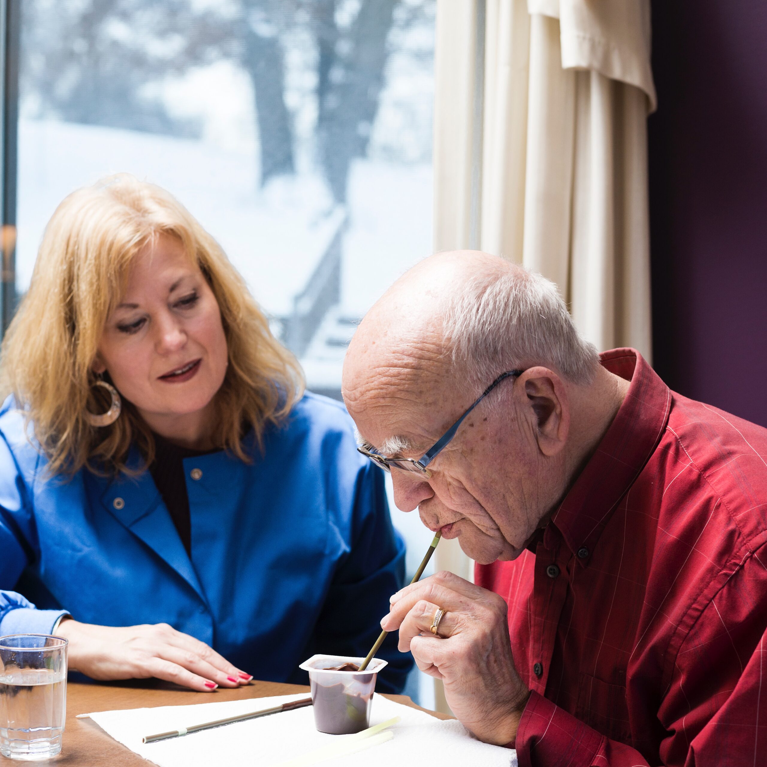 a speech therapist is helping an old man to exercise his swallowing feedback